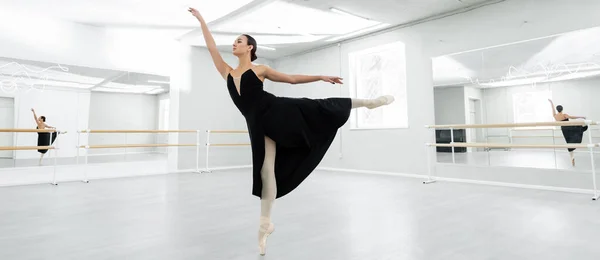 Повнометражний вид на балерину під час репетиції в просторій студії, банер — стокове фото