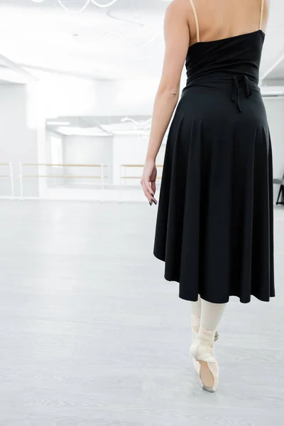 Vue arrière de ballerine recadrée en robe noire répétant en studio — Photo de stock