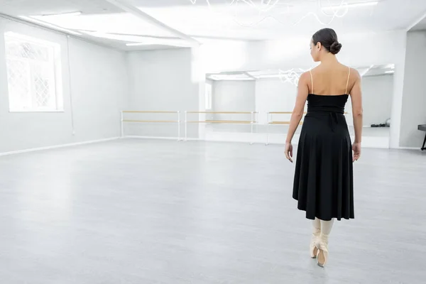 Back view of ballerina in pointe shoes standing on toes during repetition in dancing hall — Stock Photo