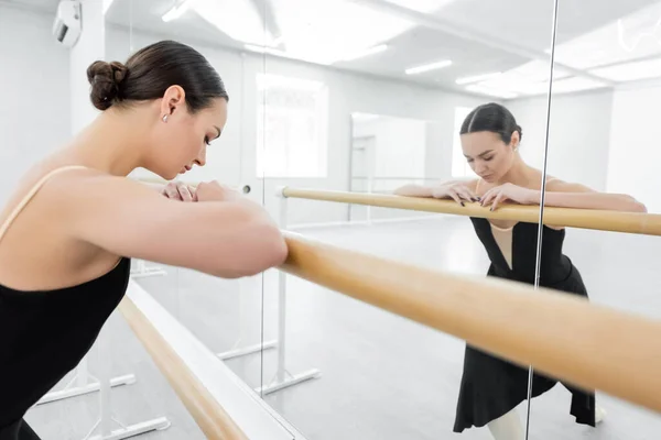 Entrenamiento de bailarina de ballet joven cerca de espejos en el estudio - foto de stock