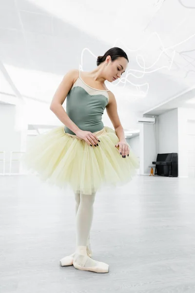 Vista completa de bailarina en tutú practicando elementos coreográficos en estudio - foto de stock