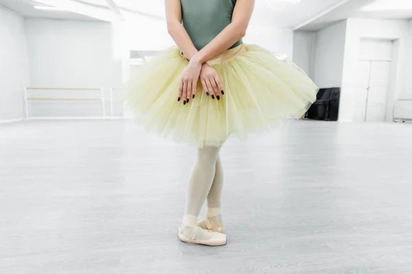 Vista cortada de bailarina em tutu e sapatos pontiagudos ensaiando no salão de dança — Fotografia de Stock