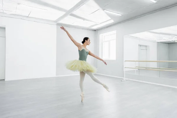 Vista completa de la elegante bailarina bailando en un amplio estudio de ballet - foto de stock