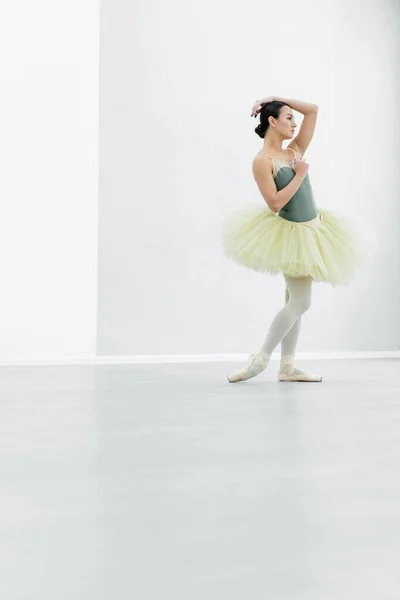 Ganzkörperansicht der jungen Ballerina, die im Tanzsaal wegschaut — Stockfoto