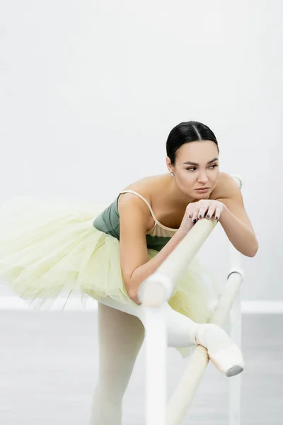 Ballerine en tutu étirement à la barre tout en s'entraînant en studio — Photo de stock