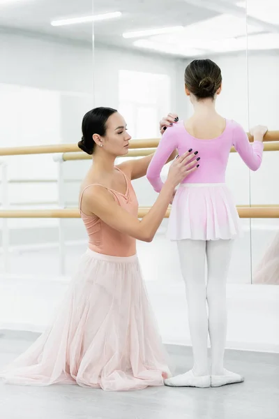 Graceful ballet master assisting girl training at barre in studio — Stock Photo