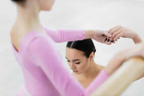 Profesora de ballet cerca de chica borrosa durante el entrenamiento en estudio de danza — Stock Photo