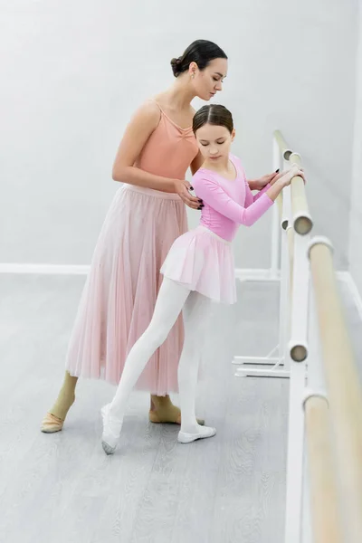 Повнометражний вигляд молодої балерини, що допомагає дев'ятнадцяти дівчатам тренуватися в студії — стокове фото