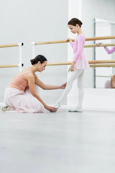 Seitenansicht einer Tanzlehrerin, die Bein eines Mädchens berührt, das in Ballettschule trainiert — Stockfoto