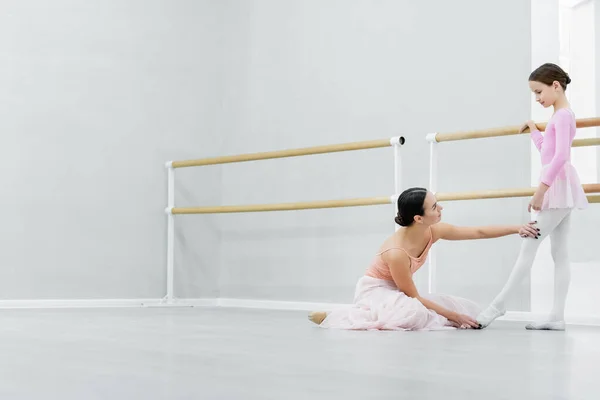 Vista lateral de ballet maestro enseñanza chica en la escuela de baile - foto de stock