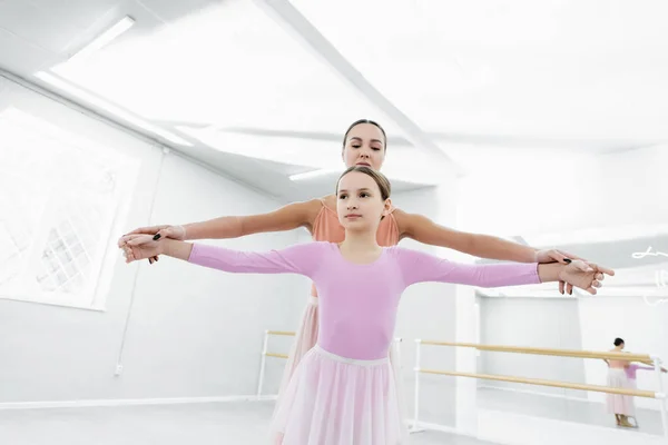 Maestro de ballet sosteniendo las manos extendidas del niño durante el entrenamiento en el estudio - foto de stock