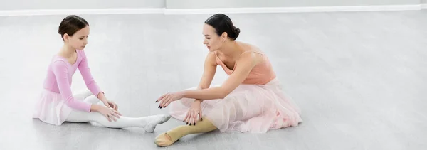 Chorégraphe pointant avec la main près de la fille étirant sur le sol en studio, bannière — Photo de stock