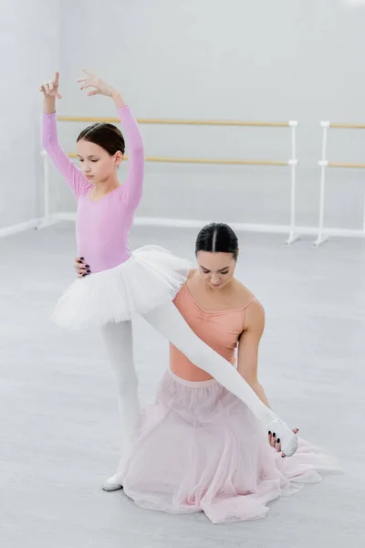 Chica con las manos levantadas aprender a bailar ballet con la ayuda de un joven profesor - foto de stock