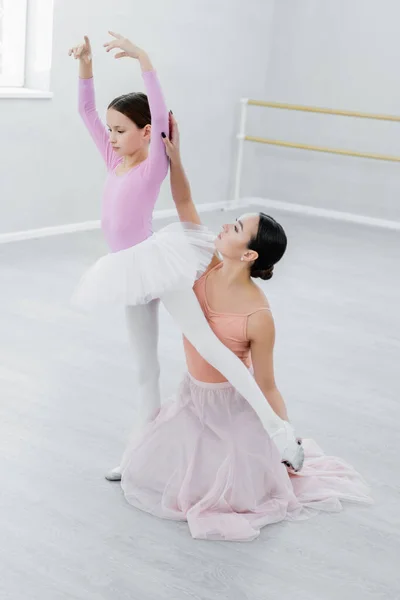 Mince fille apprendre à danser ballet avec l'aide de jeune professeur — Photo de stock