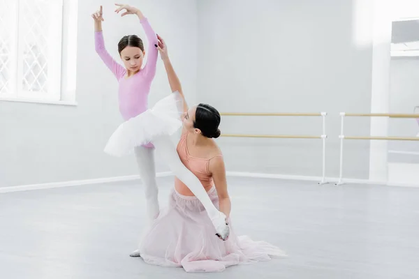 Preadolescente chica practicando elementos coreográficos cerca de joven profesor de ballet - foto de stock