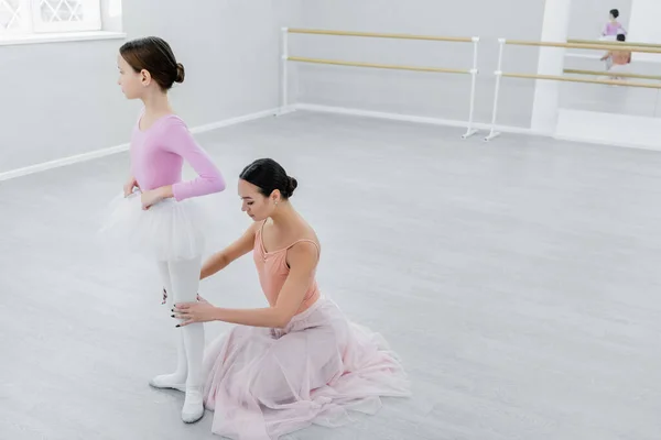 Maestro de ballet tocando rodillas de chica durante el ensayo en salón de baile - foto de stock