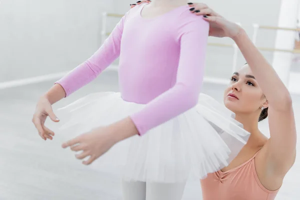 Verschwommenes Mädchen übt choreografische Elemente in der Nähe junger Ballettlehrerin — Stockfoto