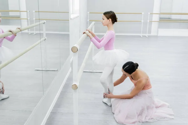 Side view of girl training in ballet school near mirrors and dance teacher — Stock Photo