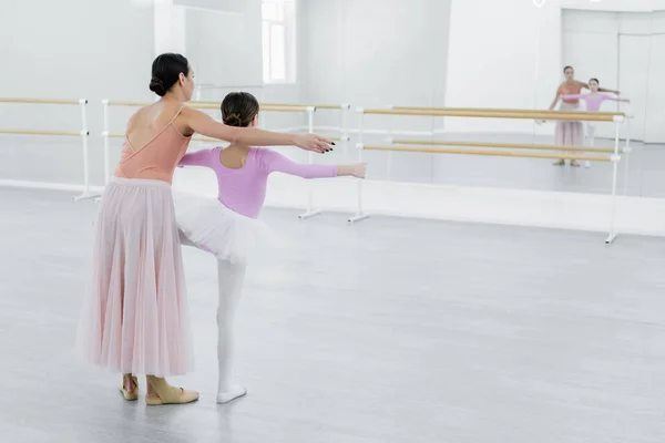 Back view of girl training in ballet school near mirrors and young dance teacher — Stock Photo