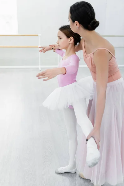 Vista lateral de chica aprendiendo elementos coreográficos cerca de maestro de ballet - foto de stock
