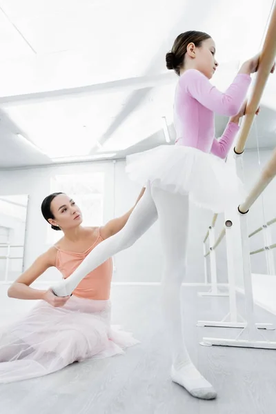 Chorégraphe tenant jambe de fille formation dans ballet école — Photo de stock