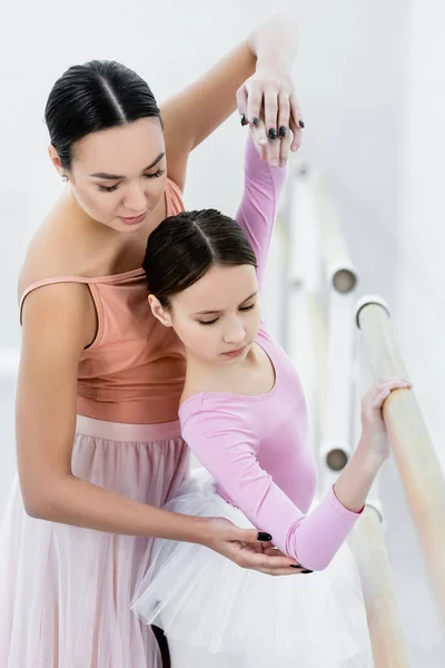 Bambino che pratica alla sbarra con l'aiuto del giovane maestro di balletto — Foto stock