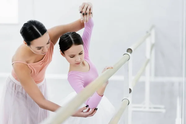 Ballettmeister unterrichtet Mädchen am Barre auf verschwommenem Vordergrund — Stockfoto