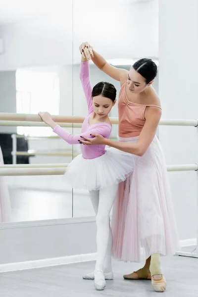 Vista completa de la formación de las niñas en la escuela de ballet cerca de joven profesor de danza - foto de stock