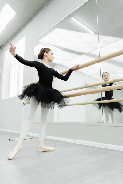 Kind im schwarzen Tutu blickt während der Wiederholung im Ballettstudio in den Spiegel — Stockfoto