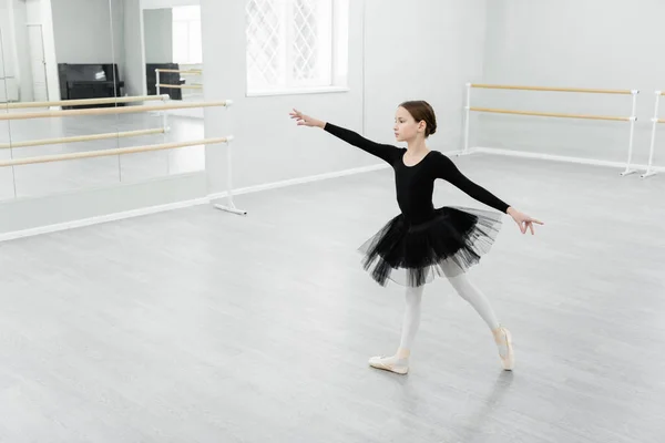 Full length view of girl in black tutu dancing during repetition in studio — Stock Photo