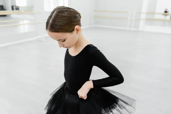 Mädchen passt schwarzes Tutu an, während sie in Ballettschule trainiert — Stockfoto