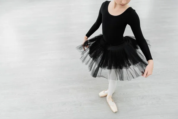 Vista cortada de menina em traje de balé preto ensaiando no salão de dança — Fotografia de Stock