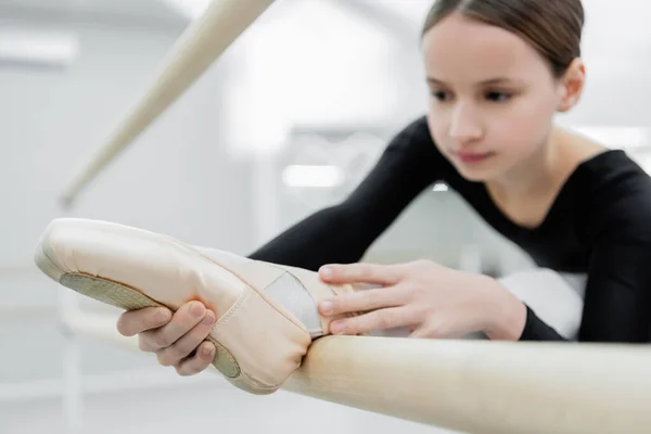 Blurred girl stretching leg while training in ballet school — Stock Photo