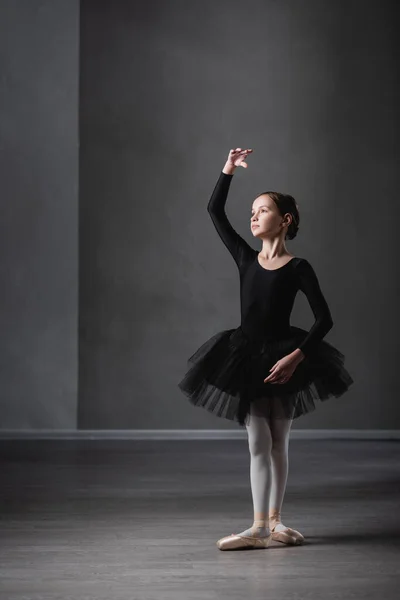 Повнометражний вигляд дівчини в чорному навчальному посібнику, що практикує хореографічні елементи в балетній студії — стокове фото