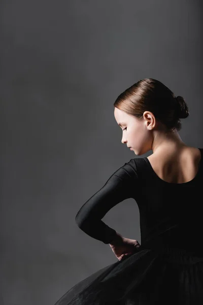 Vista trasera de la chica en traje de ballet negro sobre fondo gris - foto de stock