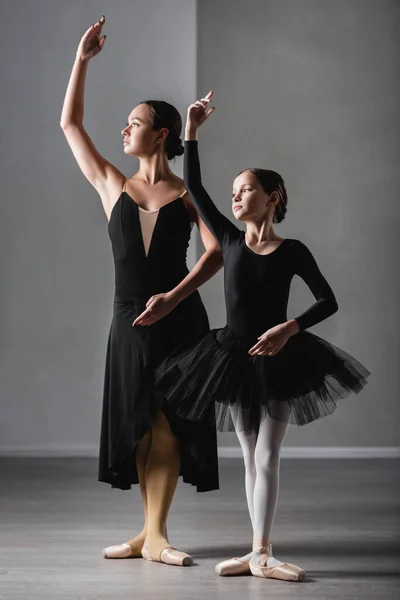 Vue pleine longueur du maître de ballet montrant des éléments chorégraphiques à la fille en tutu noir — Photo de stock