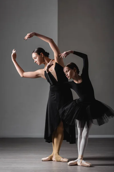 Vista completa de la muchacha en negro tutú formación cerca elegante ballet profesor - foto de stock