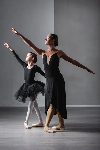 Vue complète du professeur de ballet et de la fille en tutu noir dansant pendant la leçon — Photo de stock