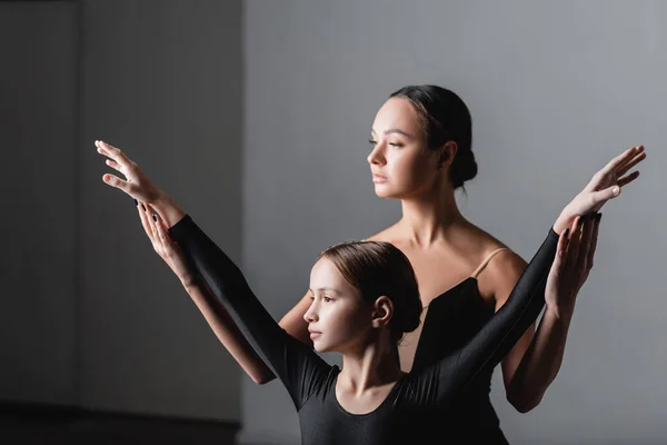 Joven profesor de ballet levantando las manos de chica durante la lección de baile - foto de stock