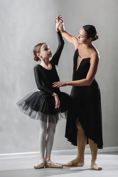 Bailarina graciosa levantando a mão da menina aprendendo a dançar balé — Fotografia de Stock