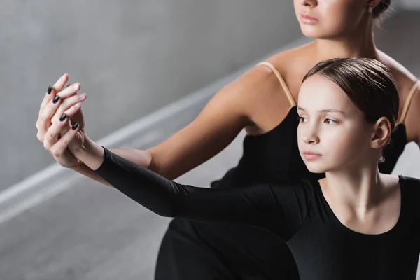 Profesora de ballet cogida de la mano de una chica durante la clase de baile - foto de stock