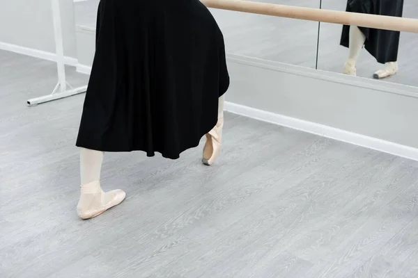 Vista cortada de bailarina em treinamento vestido preto no barre em estúdio — Fotografia de Stock