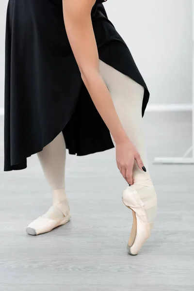 Vista recortada de bailarina en vestido negro y zapatos puntiagudos ensayando en estudio — Stock Photo