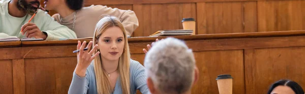 Jeune étudiant parlant à un professeur dans un auditorium universitaire, bannière — Photo de stock