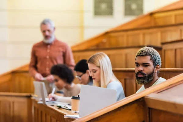 Étudiant afro-américain utilisant un ordinateur portable près des ordinateurs portables et du café à l'université — Photo de stock