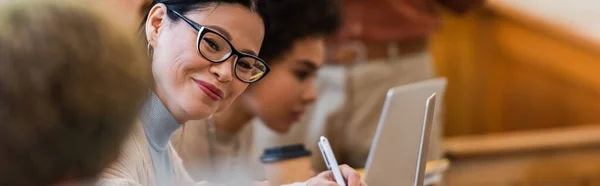 Studenti interrazziali sorridenti seduti vicino a computer portatili all'università, banner — Foto stock