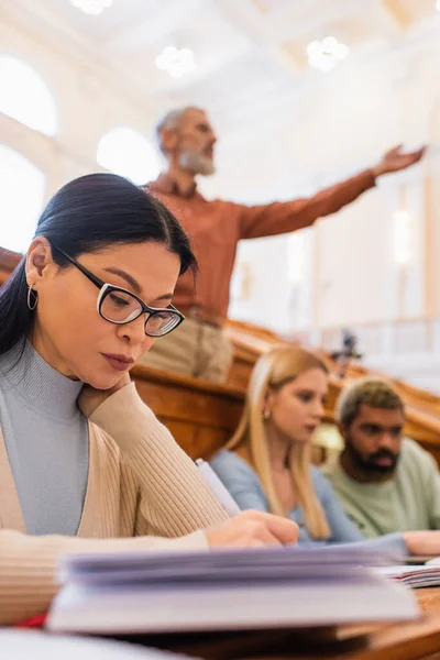 Asiatico studente scrittura su offuscata notebook in università — Foto stock