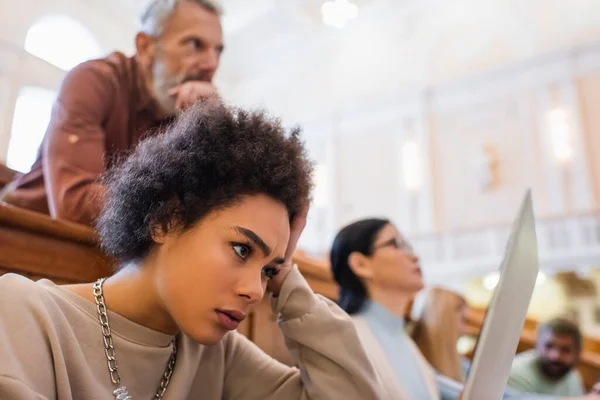 Konzentrierte afrikanisch-amerikanische Studentin schaut in der Universität auf Laptop — Stockfoto