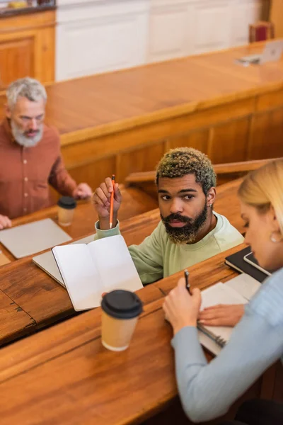 African american student pointing at notebook near friend in university — Stock Photo