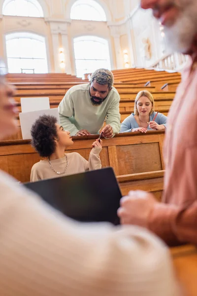 Afroamerikanische Studenten halten Kugelschreiber in der Nähe eines verschwommenen Lehrers an der Universität — Stockfoto